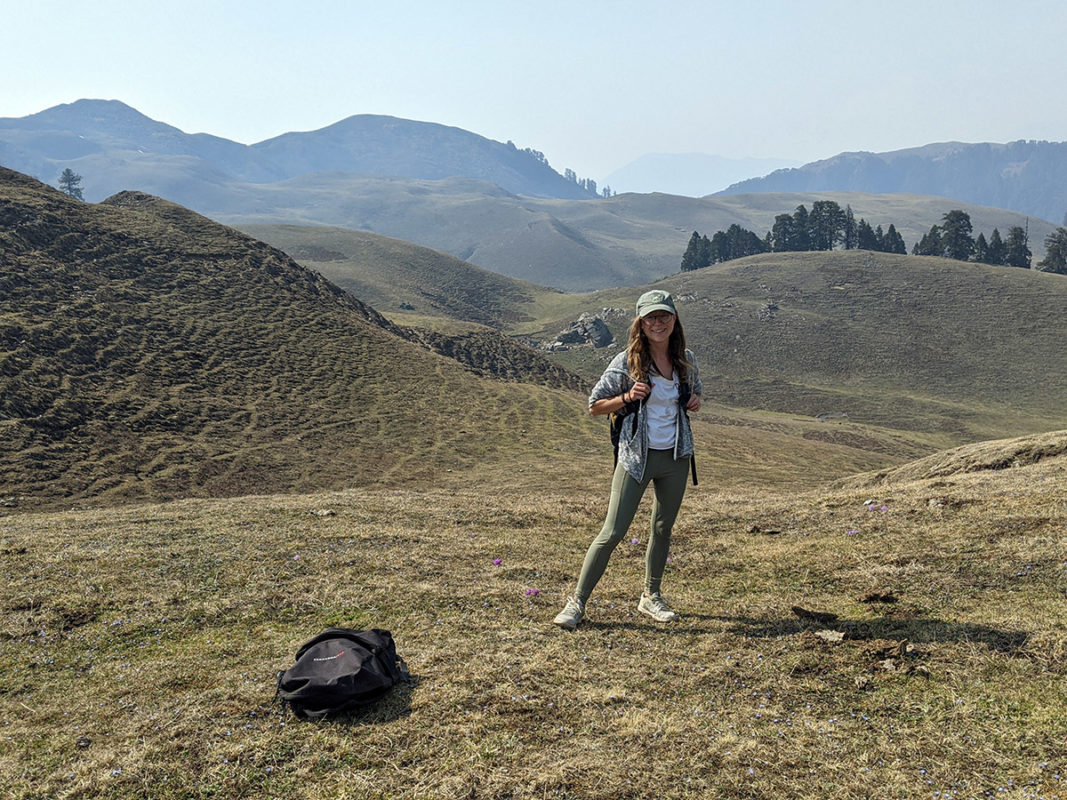 a woman standing on a hill with a backpack