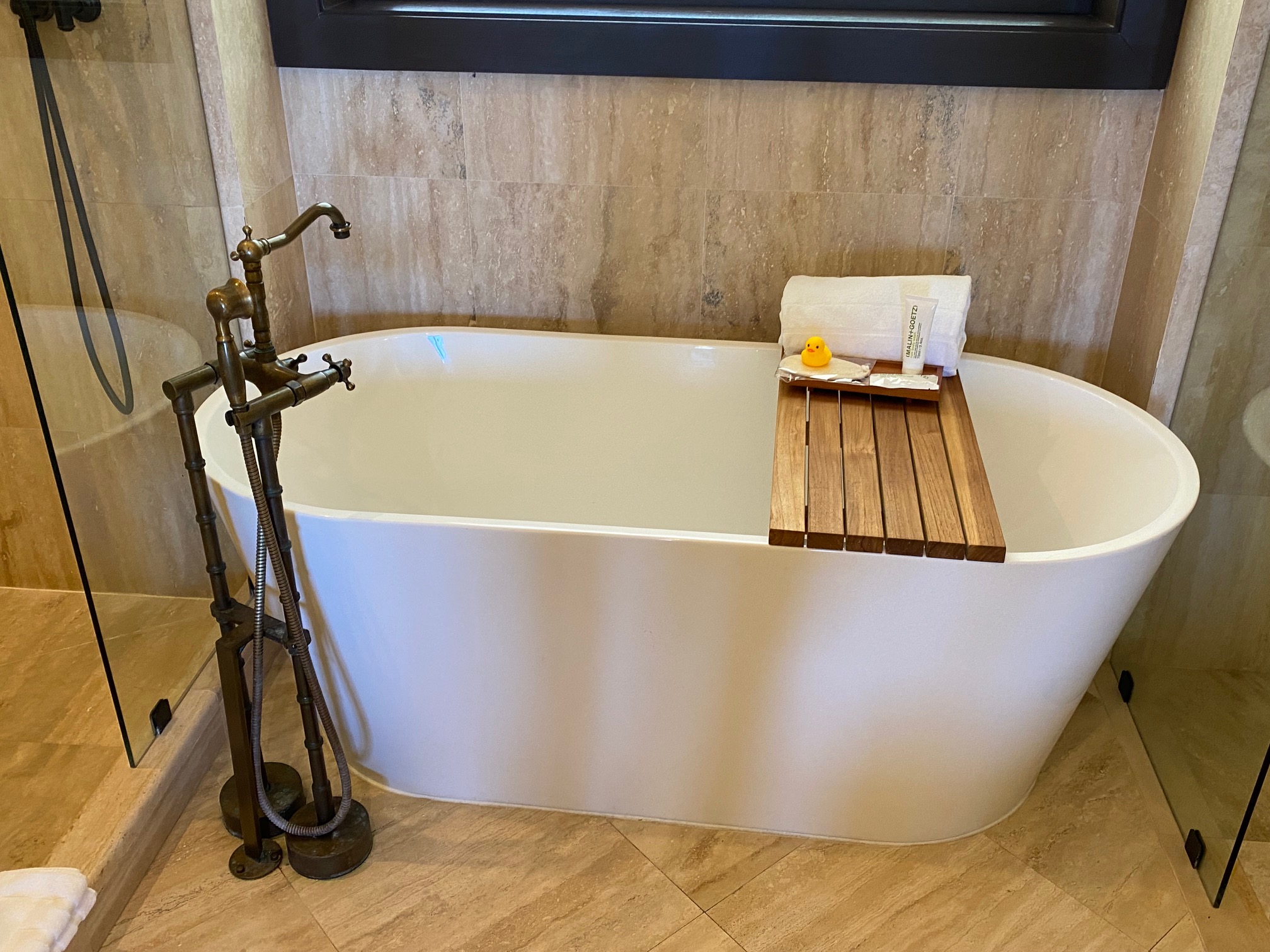 a bathtub with a wooden tray and a faucet