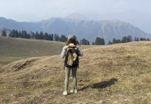 a woman standing on a hill with a backpack