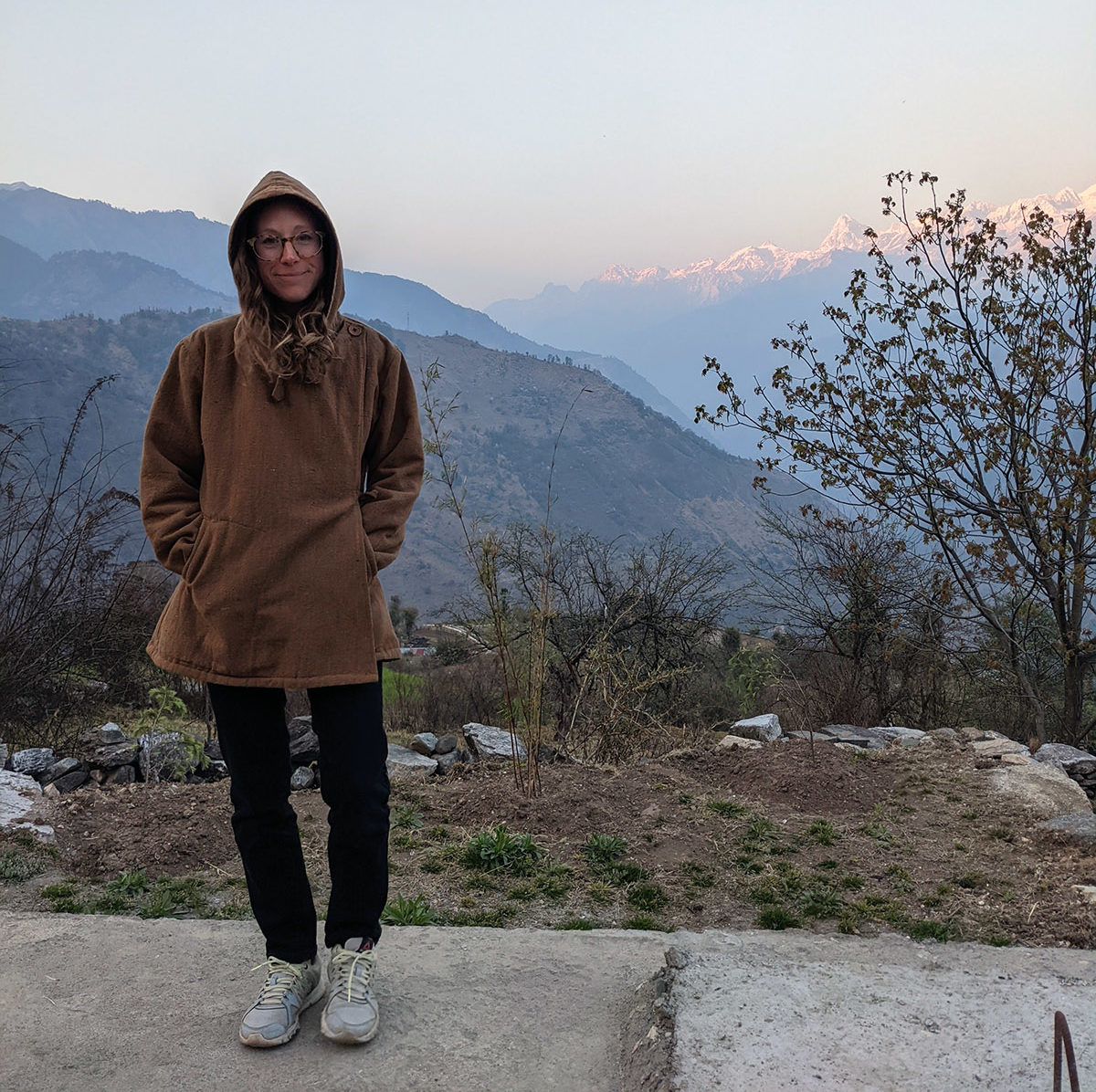 a woman standing on a sidewalk with mountains in the background