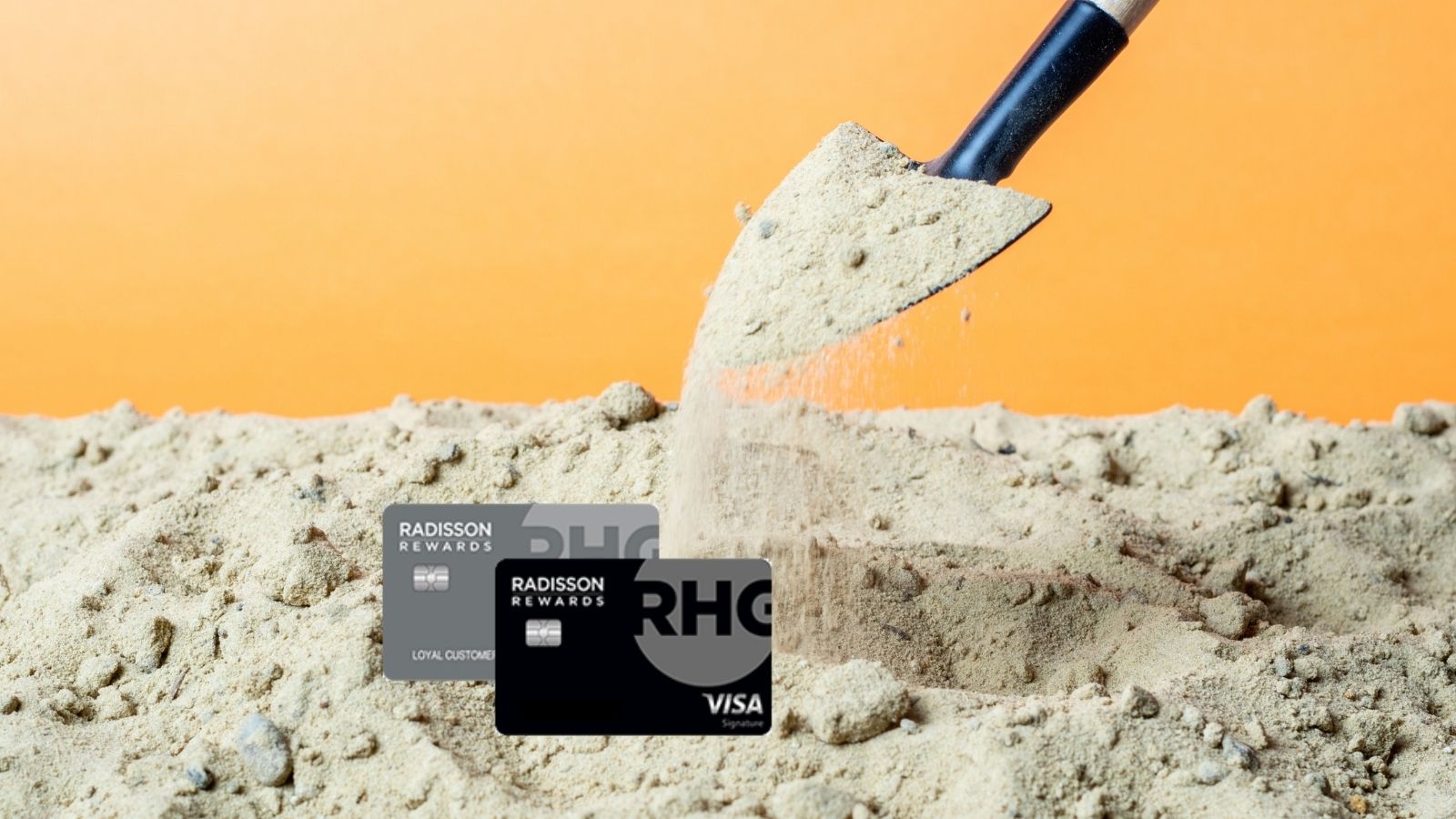 a shovel pouring sand into a pile of credit cards