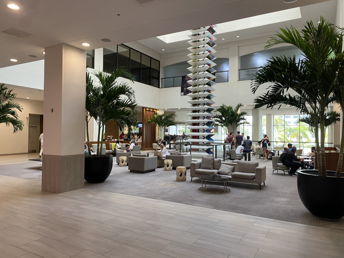 a large lobby with a tall pillar and palm trees