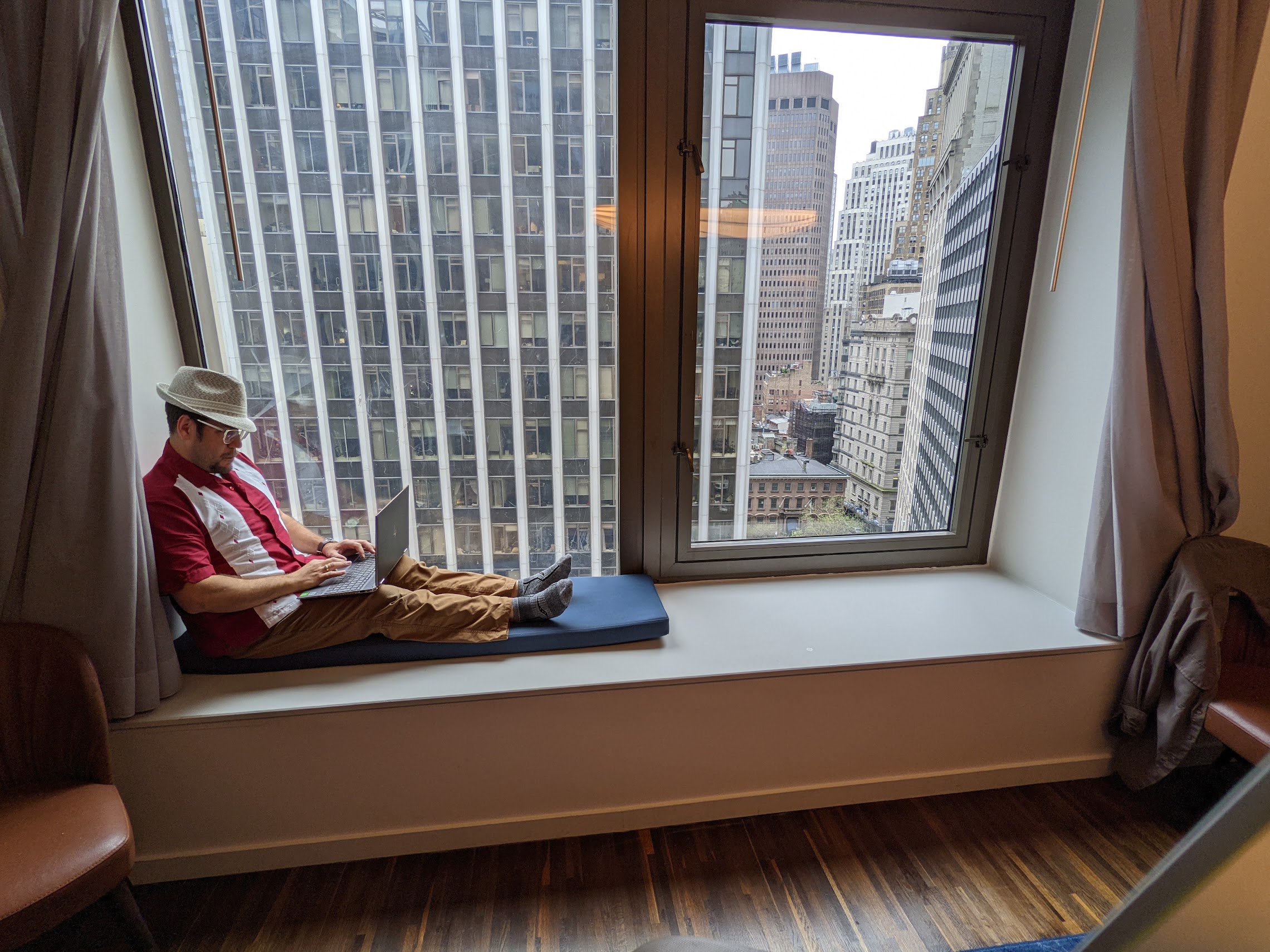 a man sitting on a window sill with a laptop