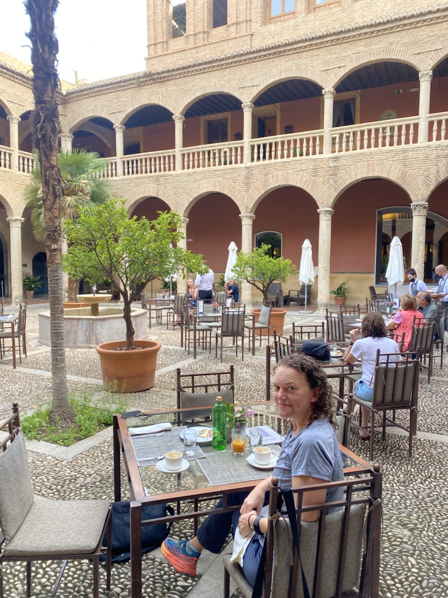 a woman sitting at a table in a courtyard