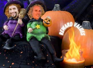 two men in clothing sitting on a couch with pumpkins and a candle