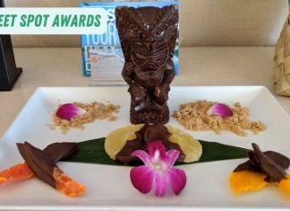 a chocolate tiki statue on a white plate with flowers