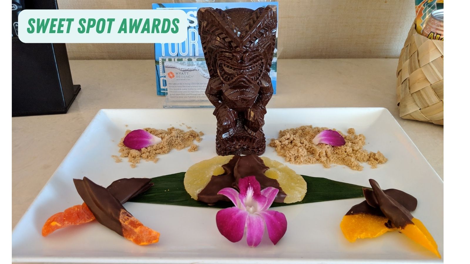 a chocolate tiki statue on a white plate with flowers