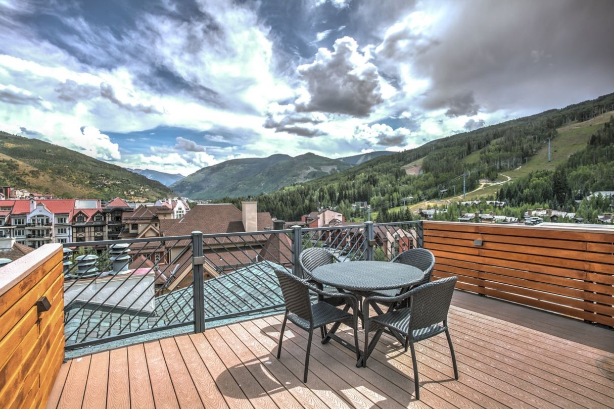 a table and chairs on a deck overlooking a valley