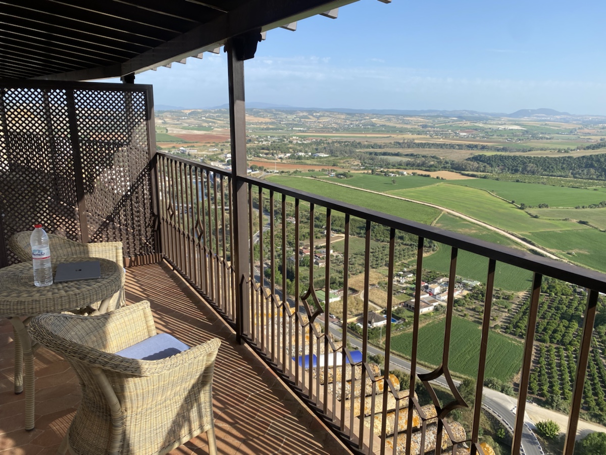 a balcony with chairs and a view of fields and roads