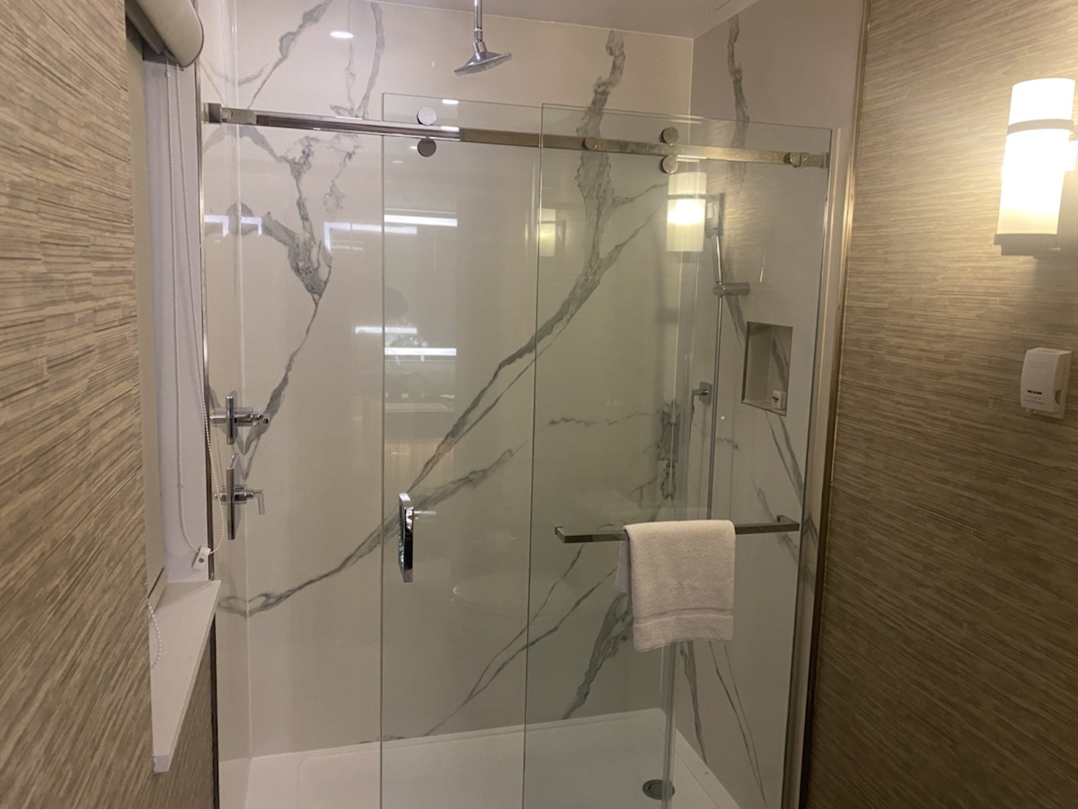 a glass shower with a white towel on a bar