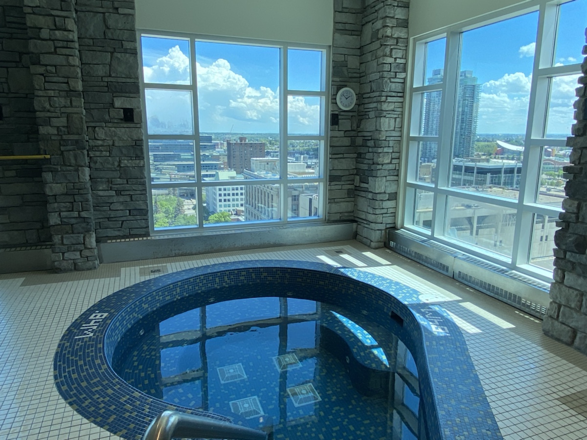 a large indoor hot tub with a stone wall and a large window