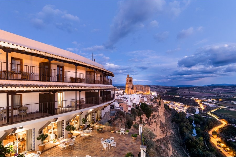 a building with a balcony and tables on a cliff