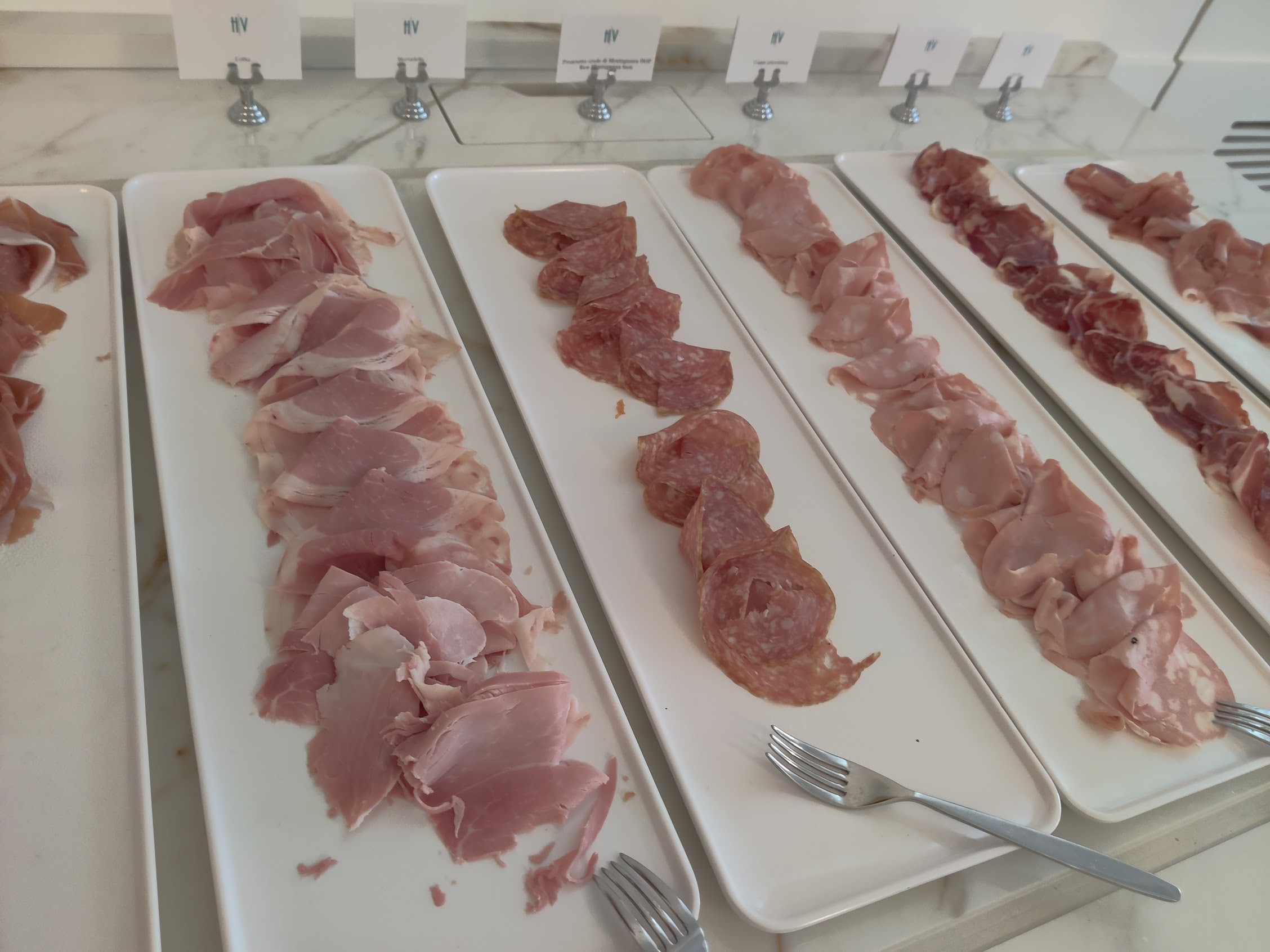 a row of different types of meat on white plates