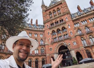 a man in a hat and glasses in front of St Pancras railway station
