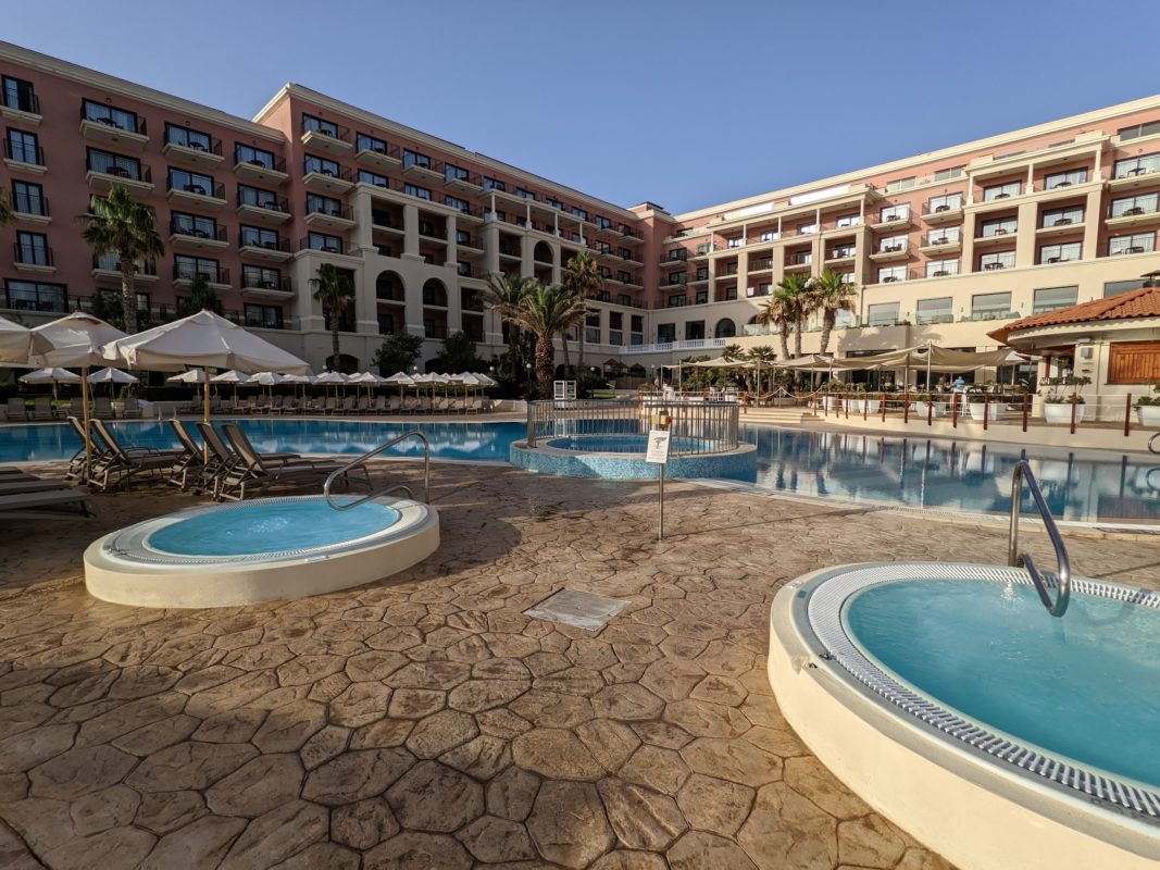 a pool with hot tubs and umbrellas in front of a building