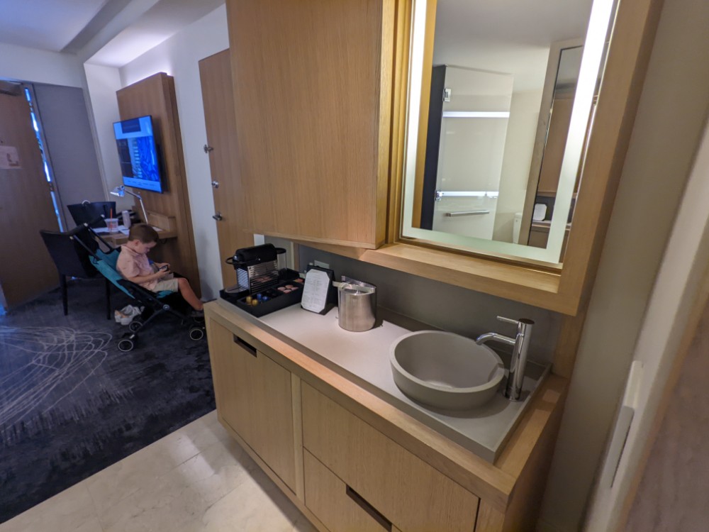 a child sitting in a chair in a room with a sink and mirror
