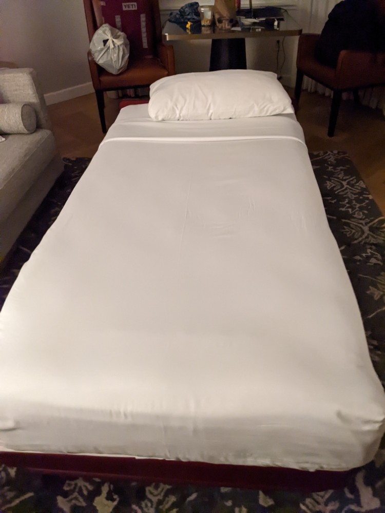 a bed with a white sheet and a pillow