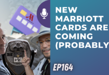 a man with glasses and hat holding up his finger