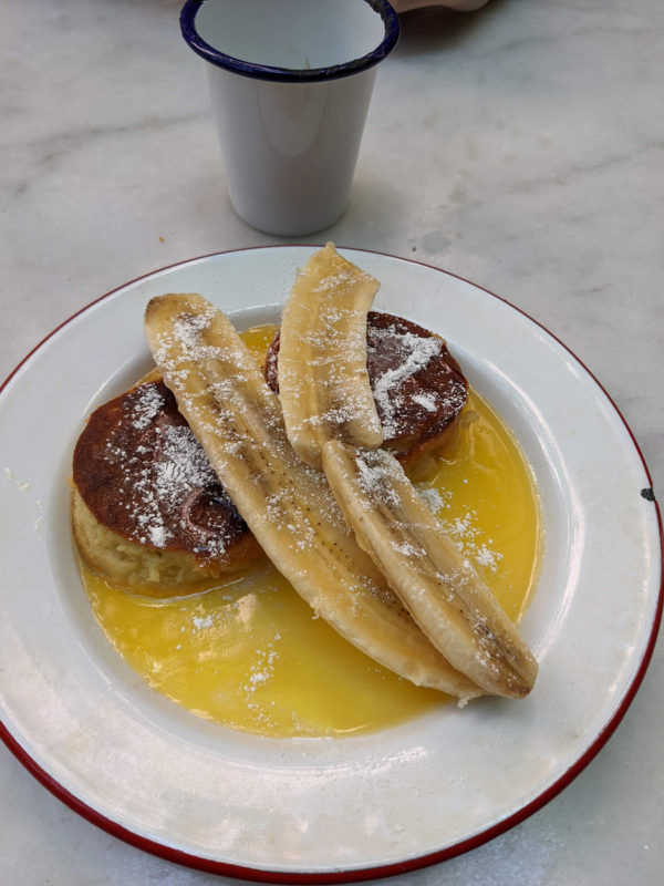 a plate of pancakes with bananas and syrup