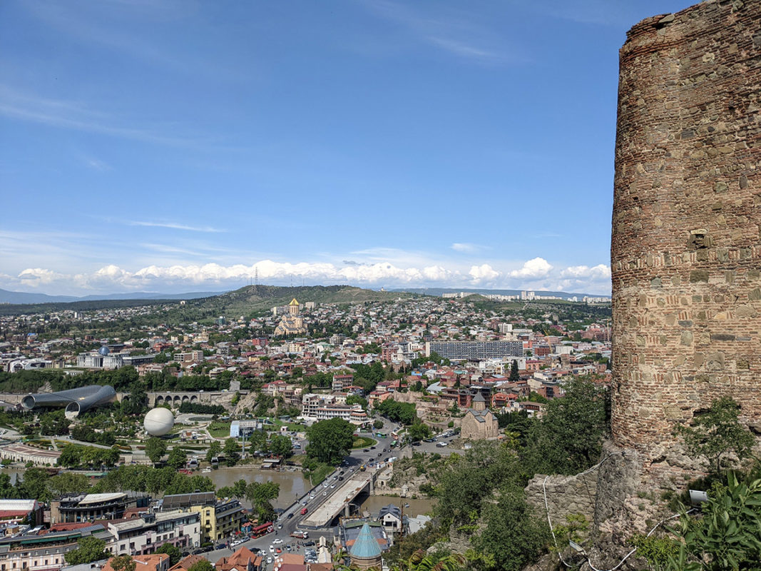 a tall stone tower on a rocky cliff above a city
