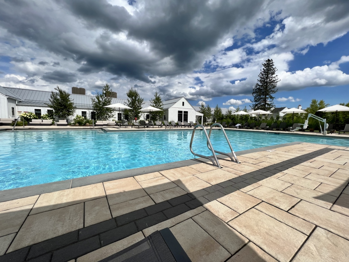a pool with a white building and clouds in the sky