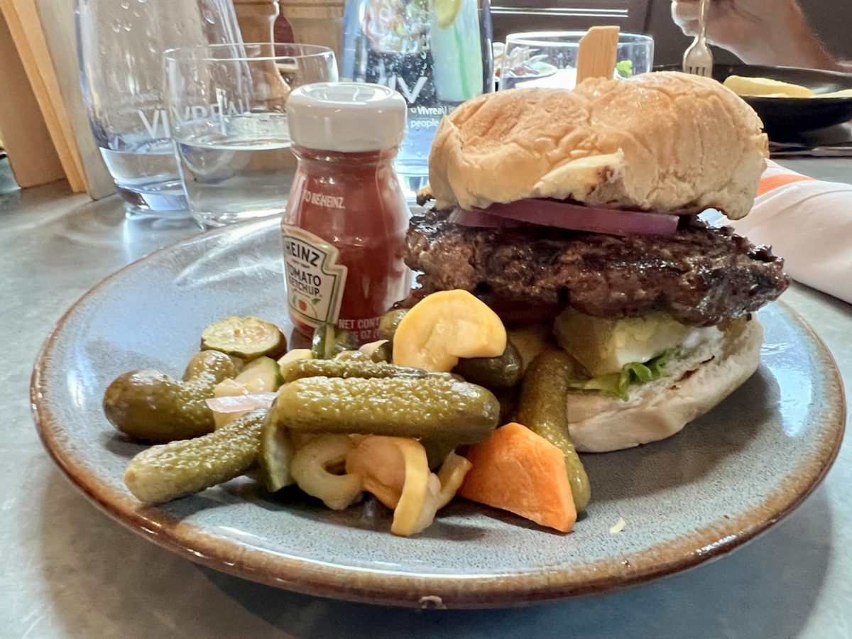 a plate of food with a burger and pickles