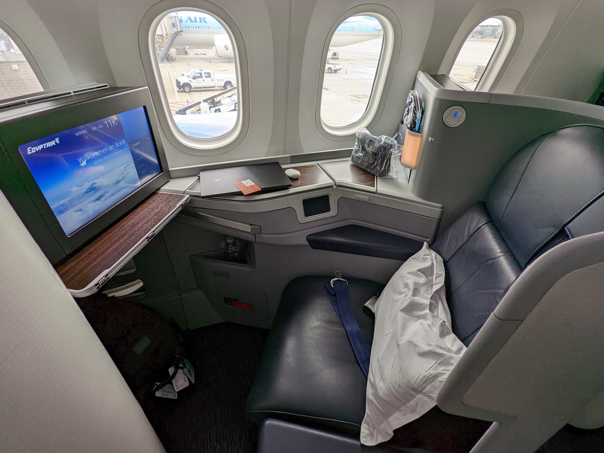 a seat in an airplane with a computer and a pillow