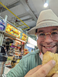 a man wearing a hat and glasses holding food