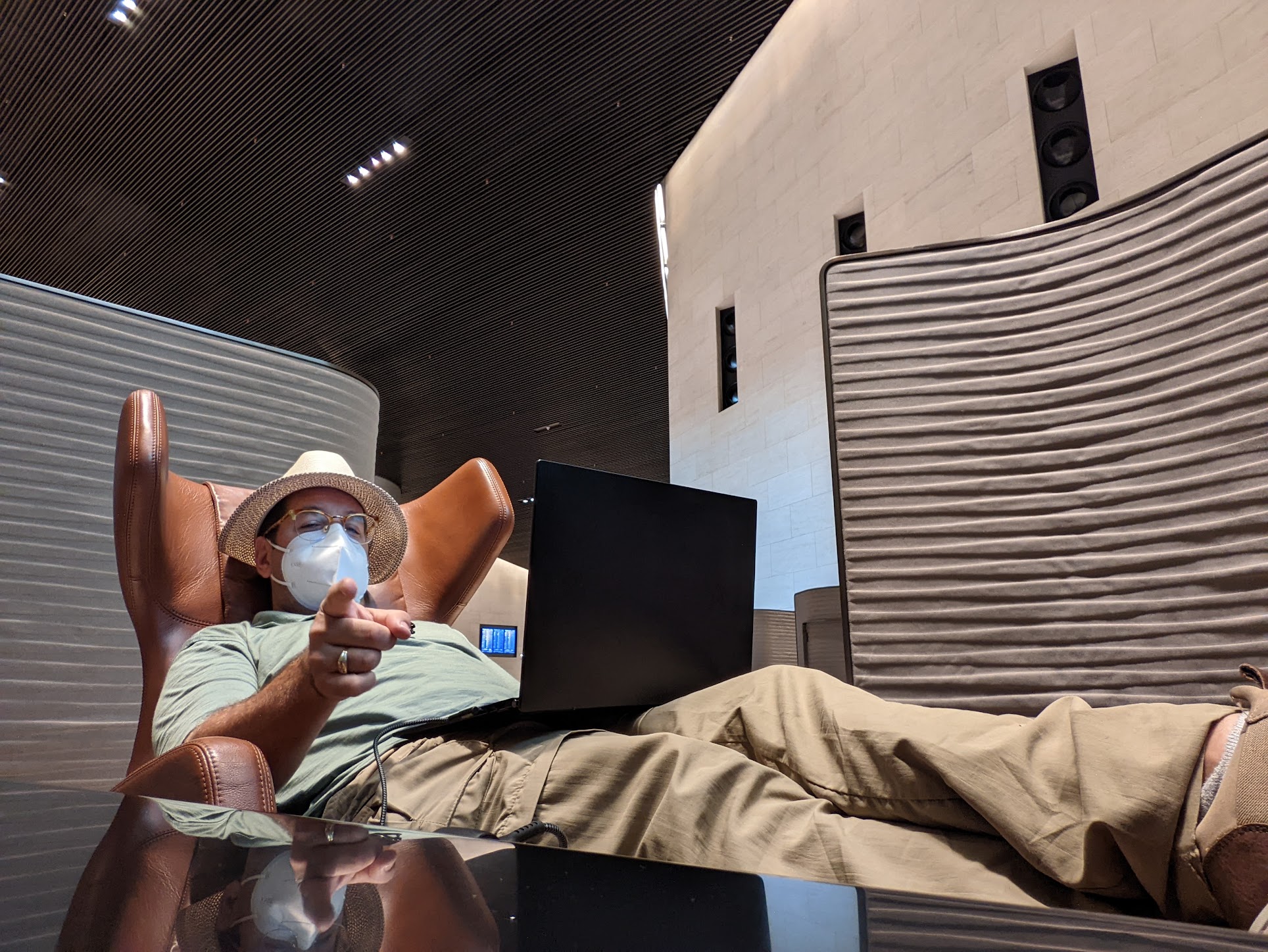 a man lying in a chair with a laptop pointing at the camera