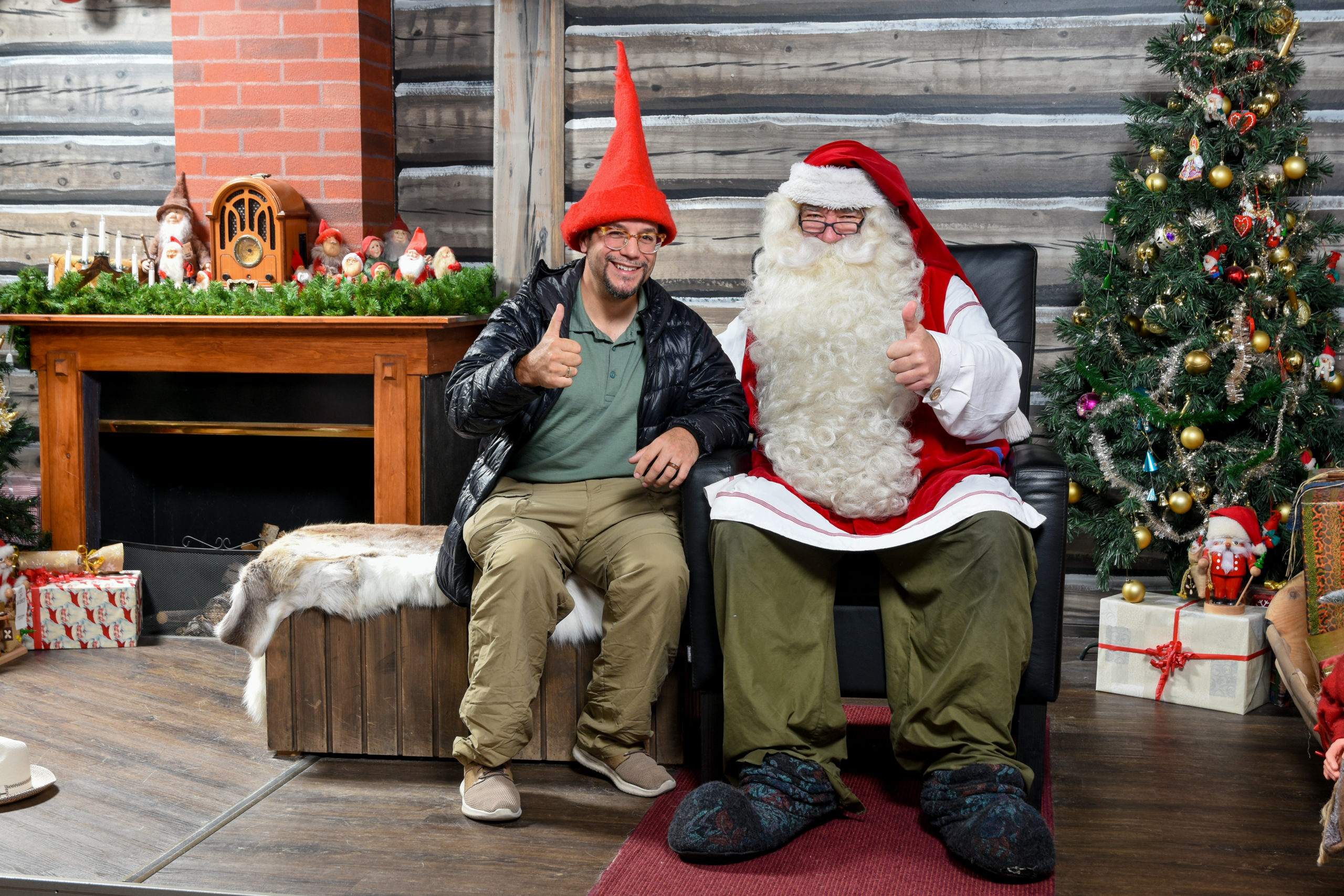 two men sitting on a couch with a santa claus garment