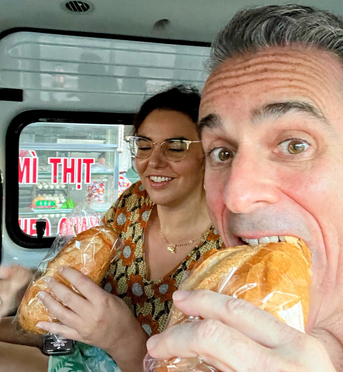 a man and woman eating bread in a van