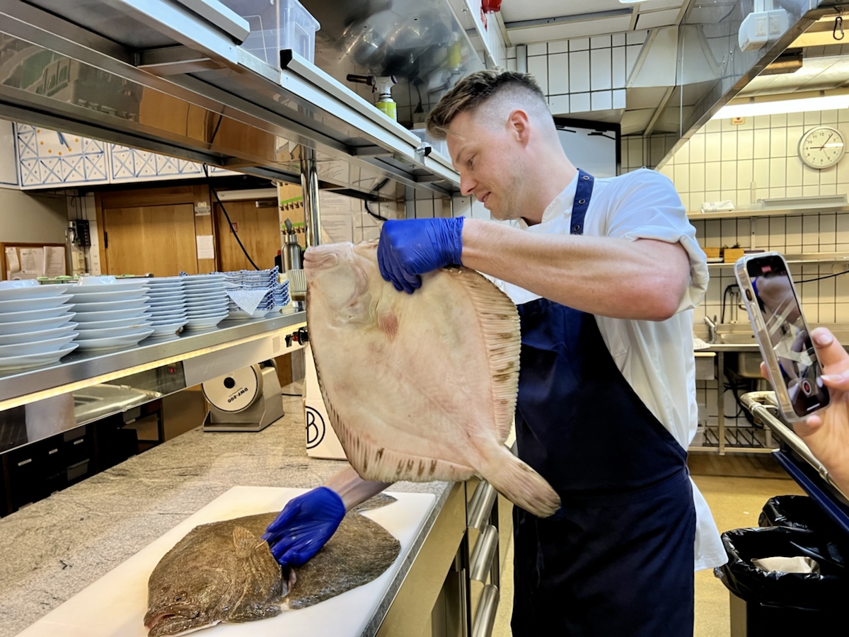a man in a kitchen holding a flounder
