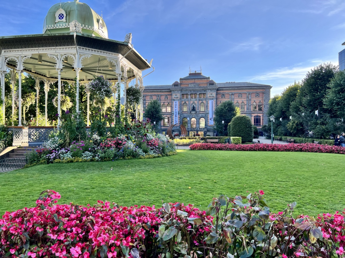 a large lawn with flowers and a gazebo in the foreground