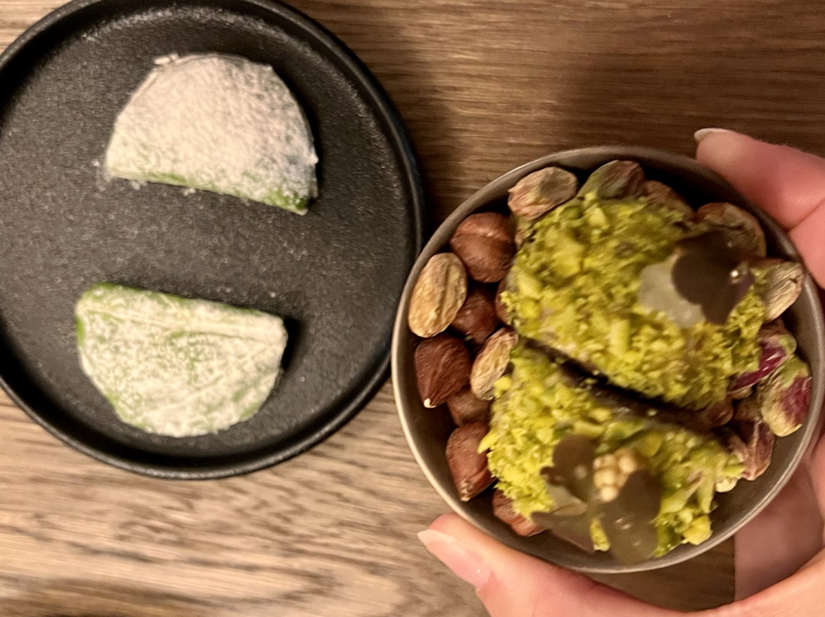 a hand holding a bowl of food next to a plate of food
