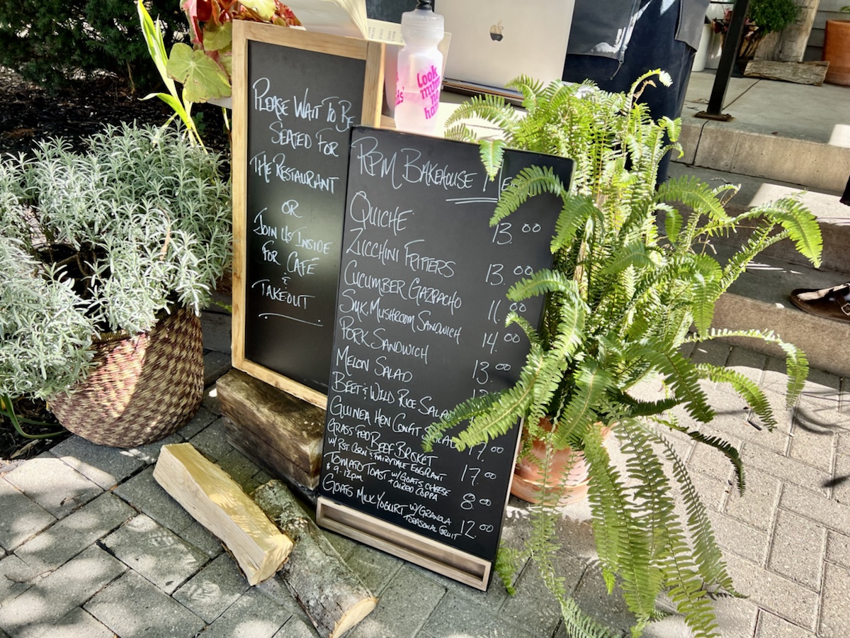 a chalkboard sign with a plant in front of it