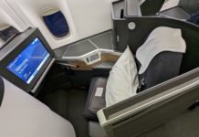 a seat with a monitor and a pillow on the side of the seat