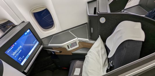 a seat with a monitor and a pillow on the side of the seat