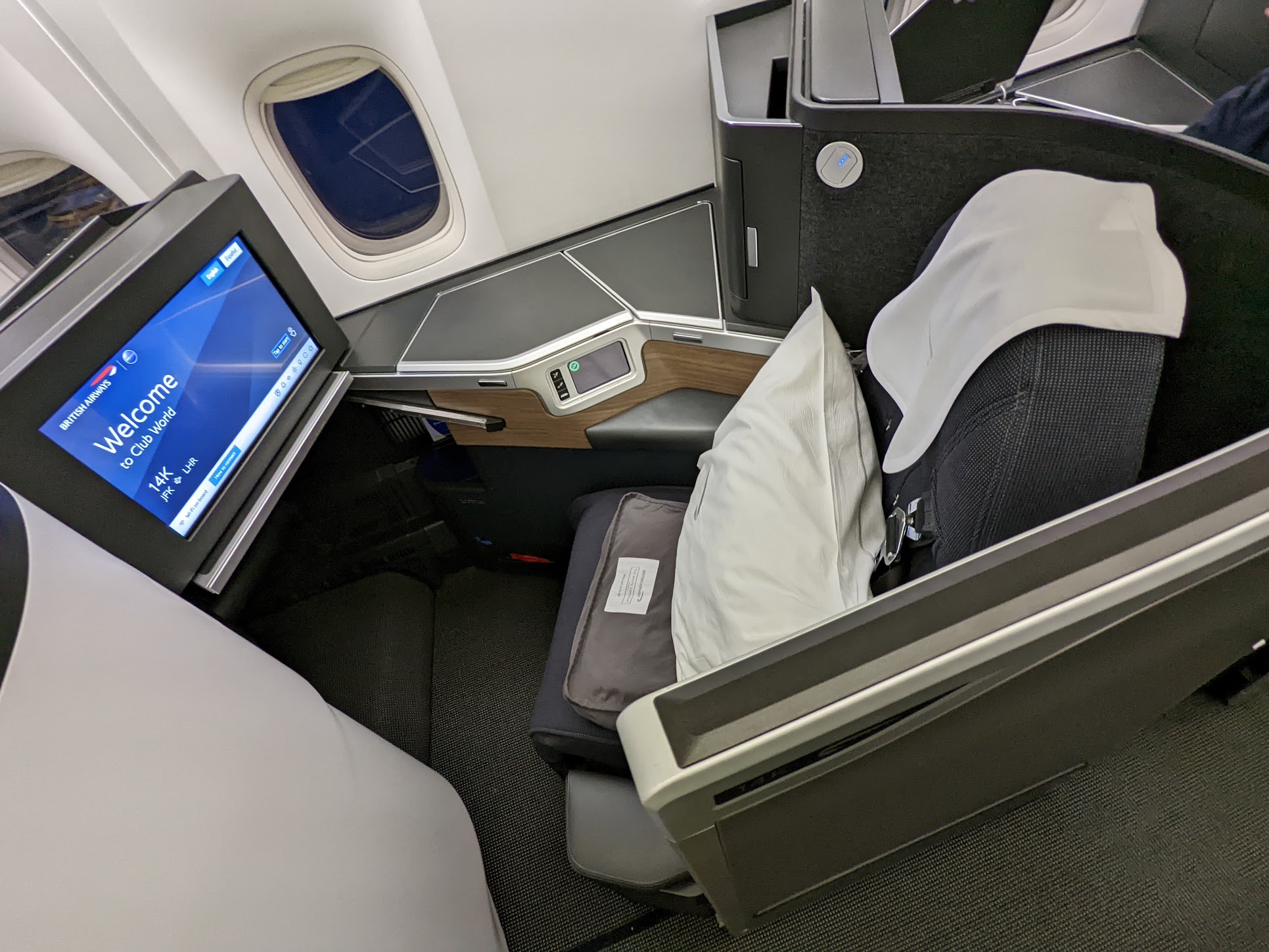 a seat with a monitor and a pillow on the side of the seat