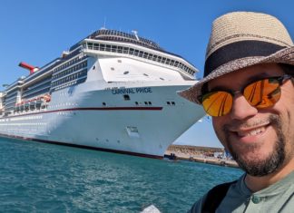 a man taking a selfie in front of a cruise ship