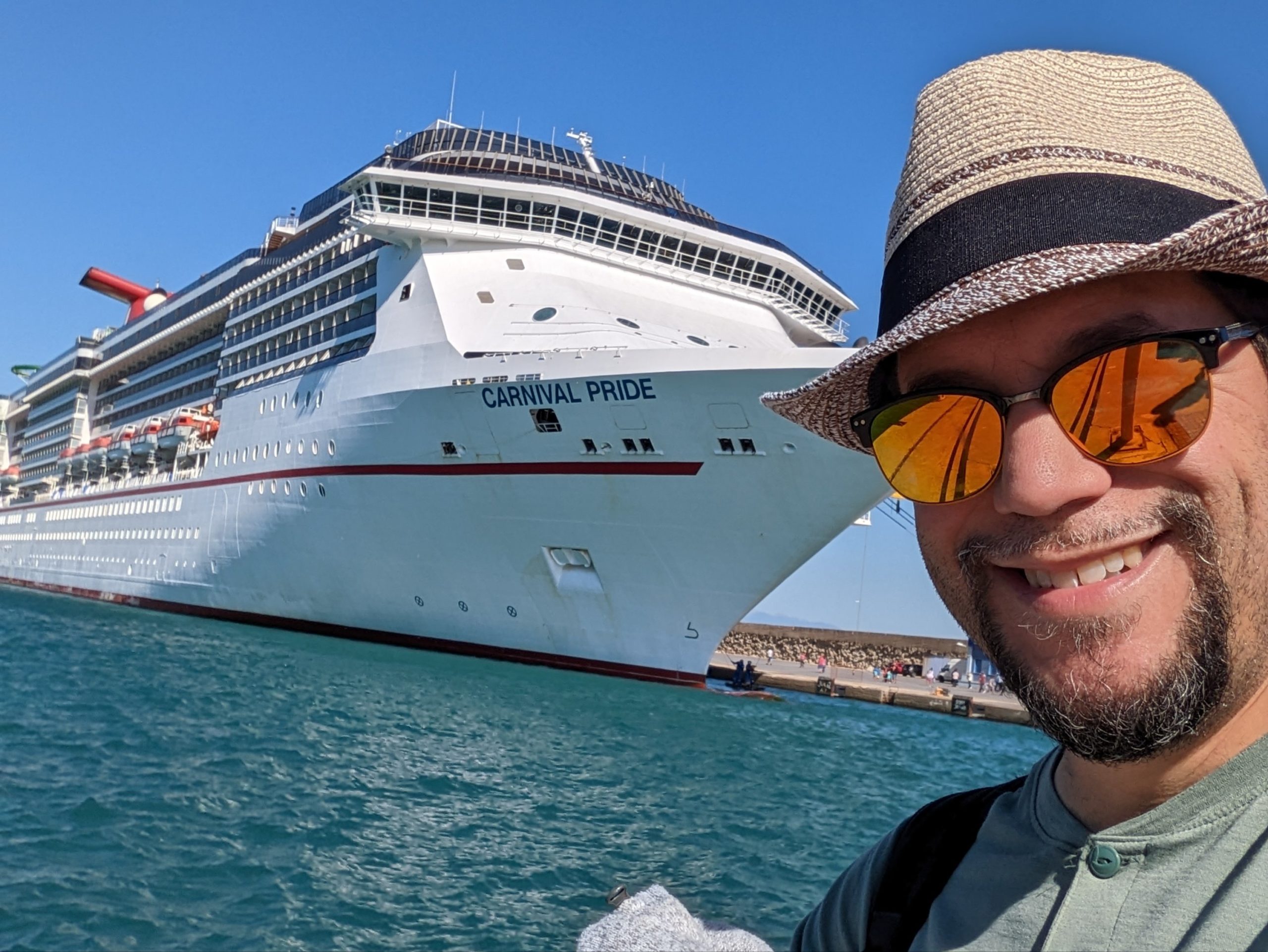 a man taking a selfie in front of a cruise ship