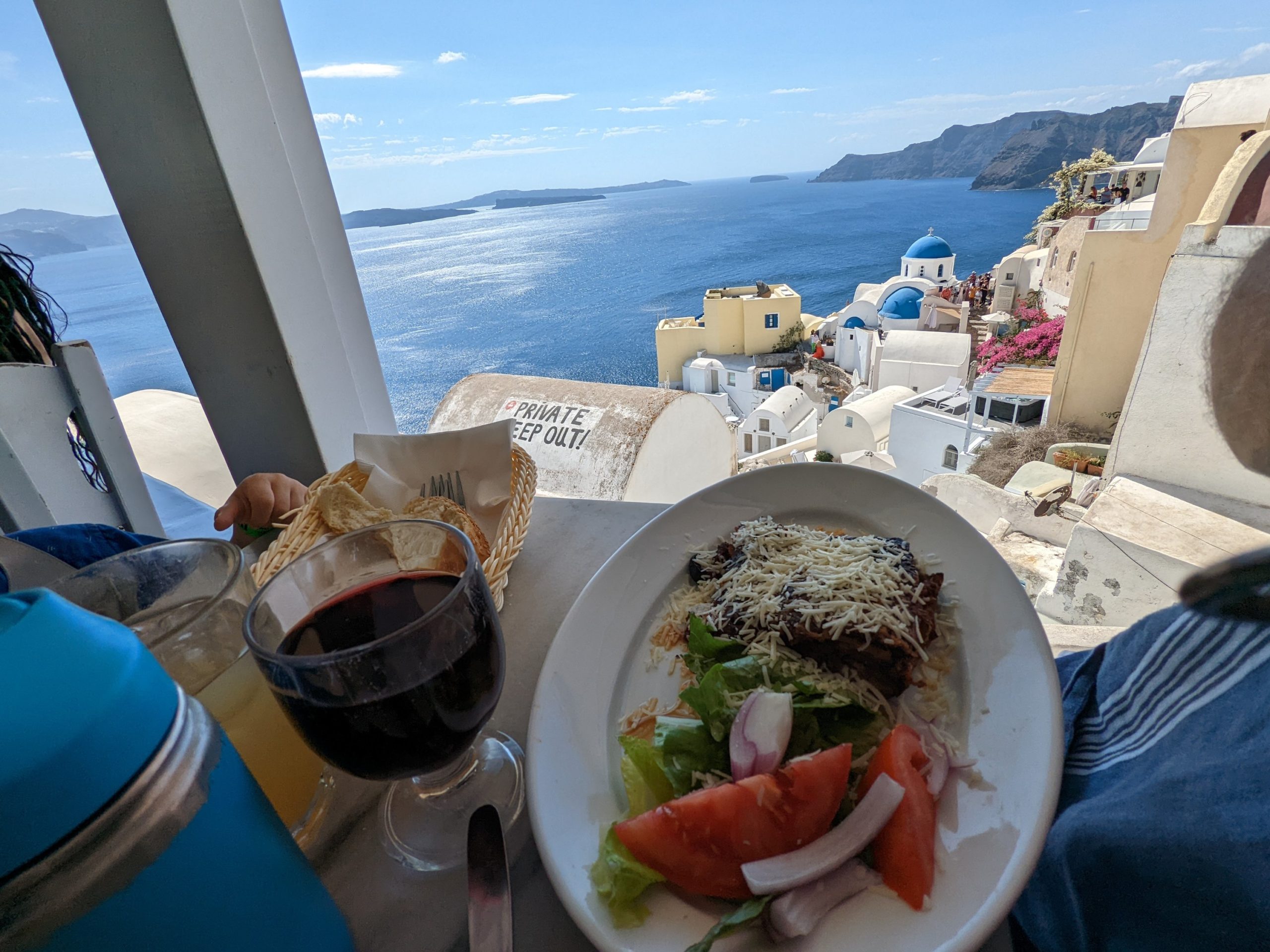 a plate of food and a glass of wine on a table overlooking a body of water