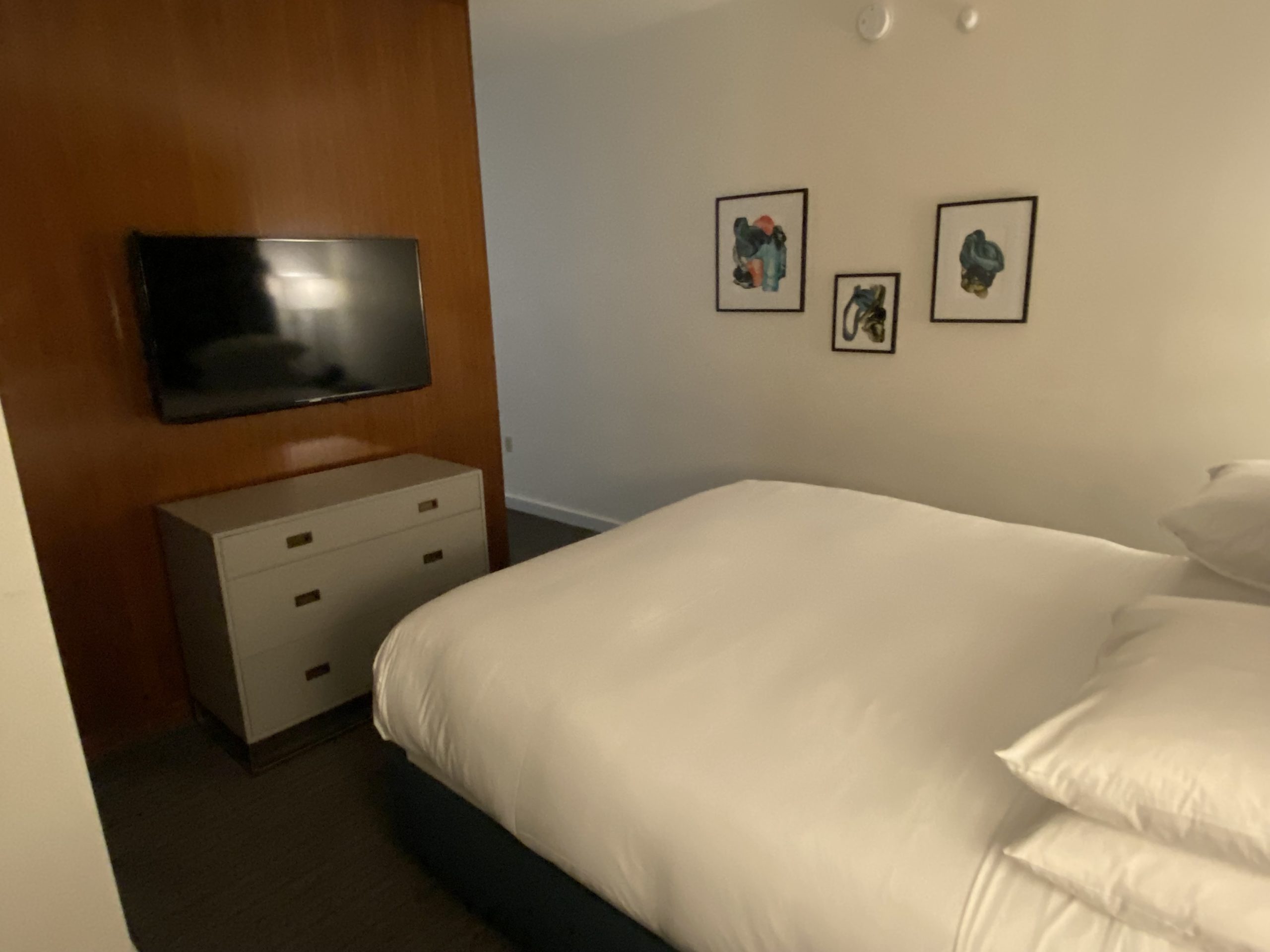 a bed with a white sheet and a tv on the wall
