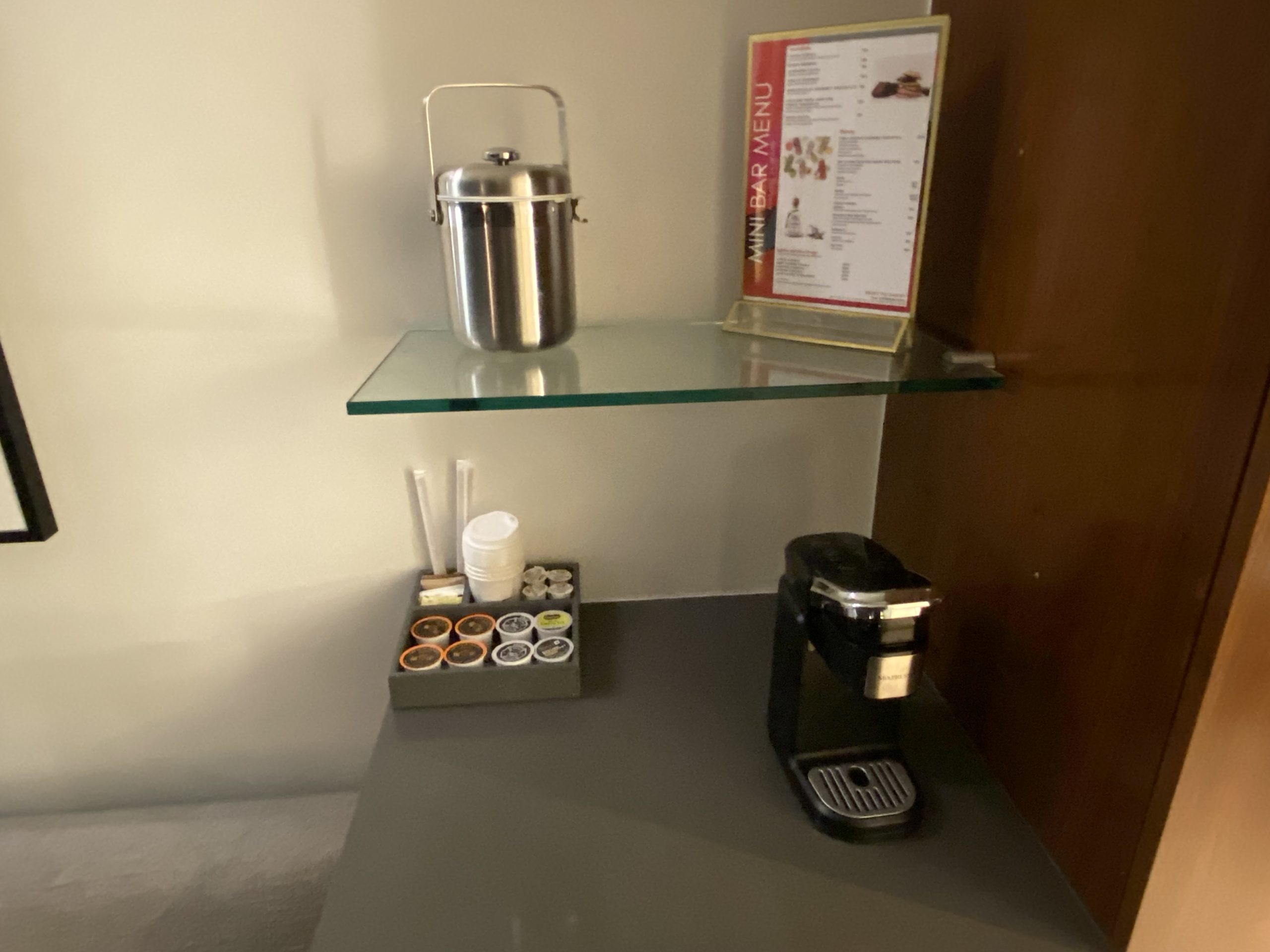 a glass shelf with a coffee maker and a menu