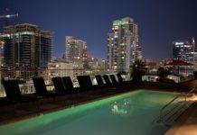 a pool with chairs and a city skyline at night