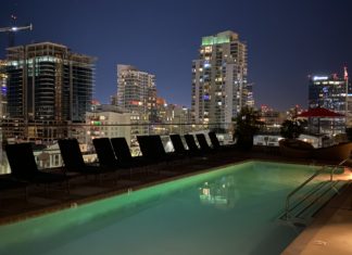 a pool with chairs and a city skyline at night