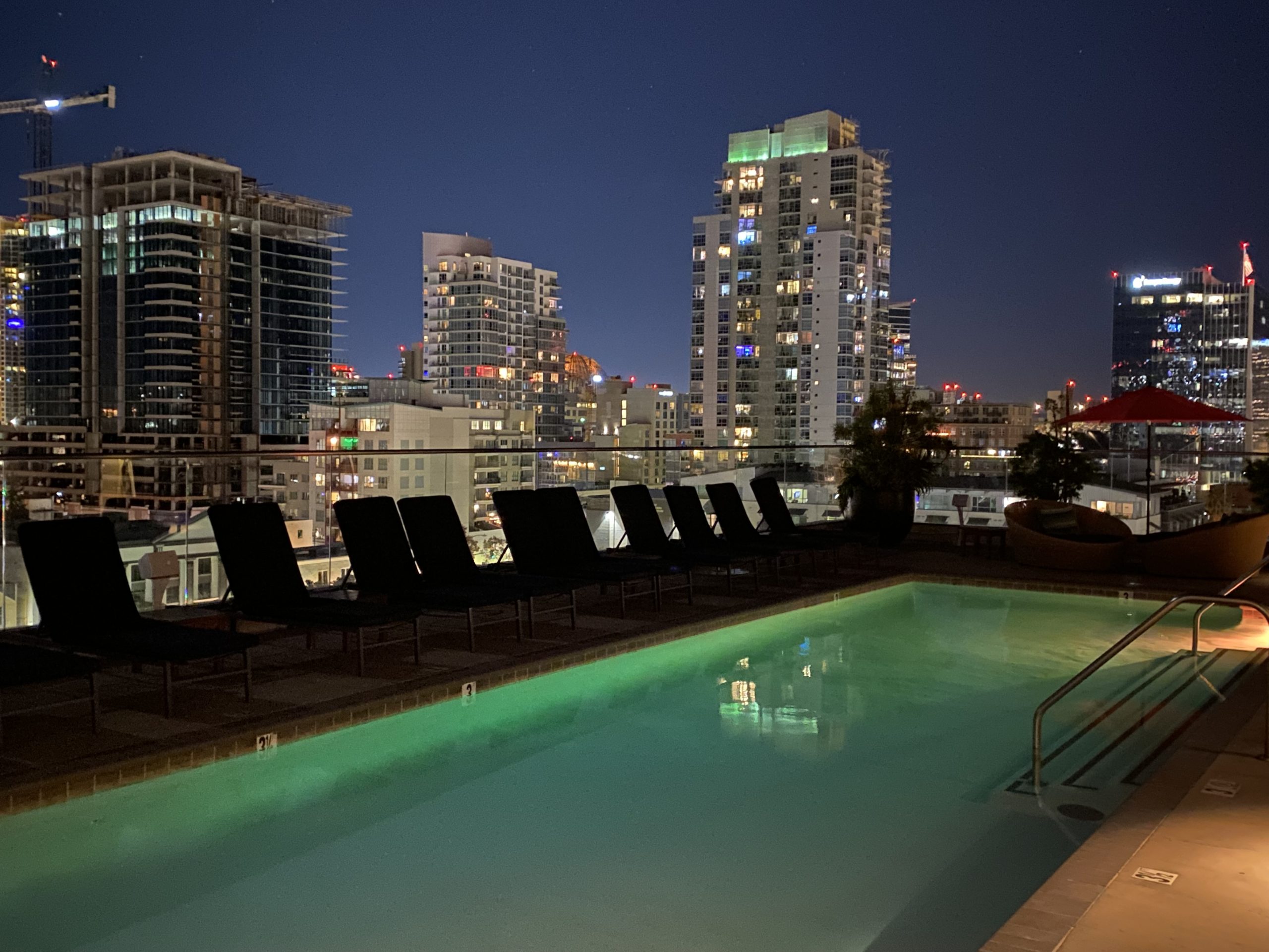 a pool with chairs and a city skyline at night