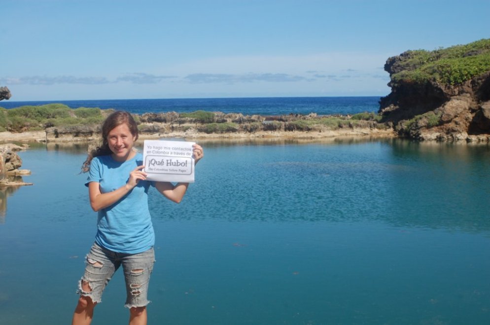 a woman holding a sign in front of a body of water
