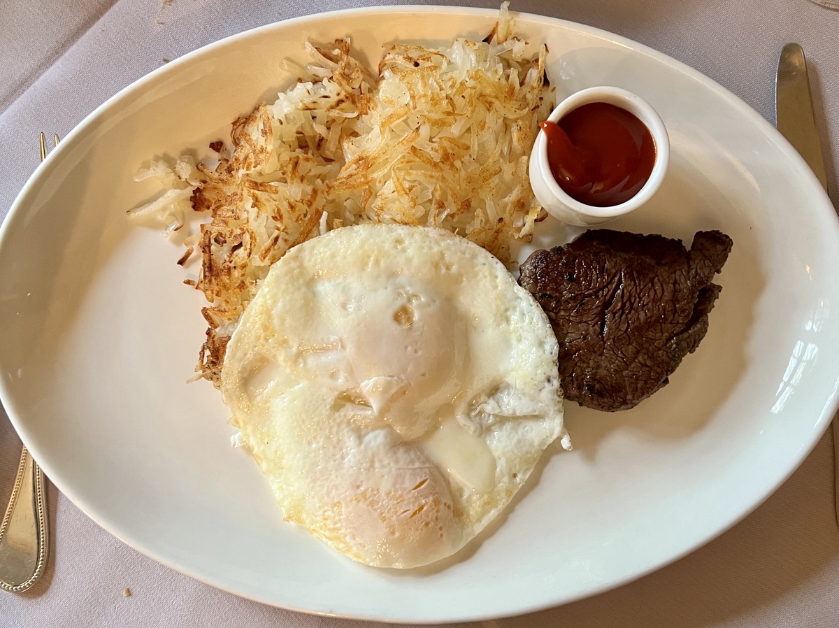 a plate of food with a steak egg and hash browns