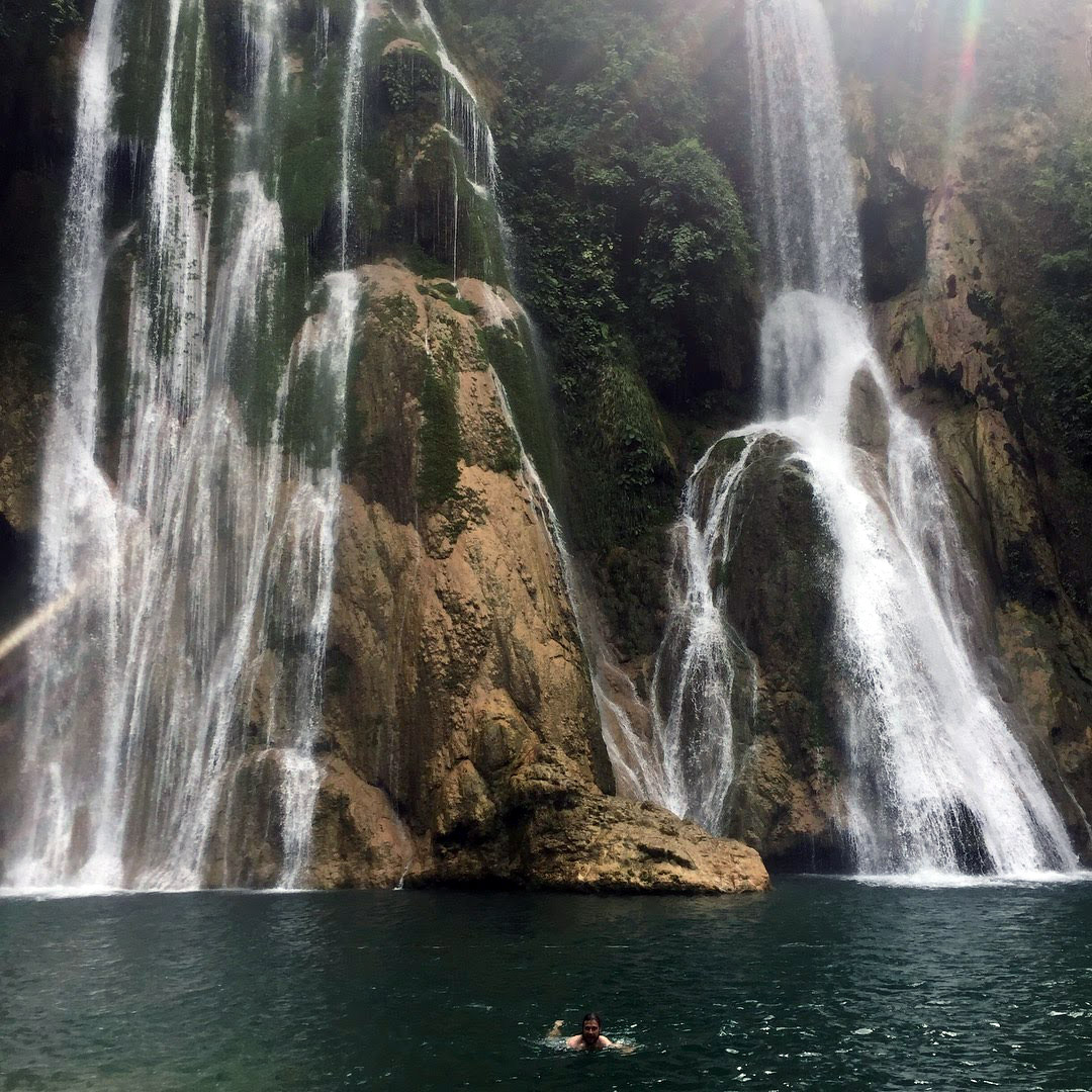 a person swimming in a body of water with a waterfall