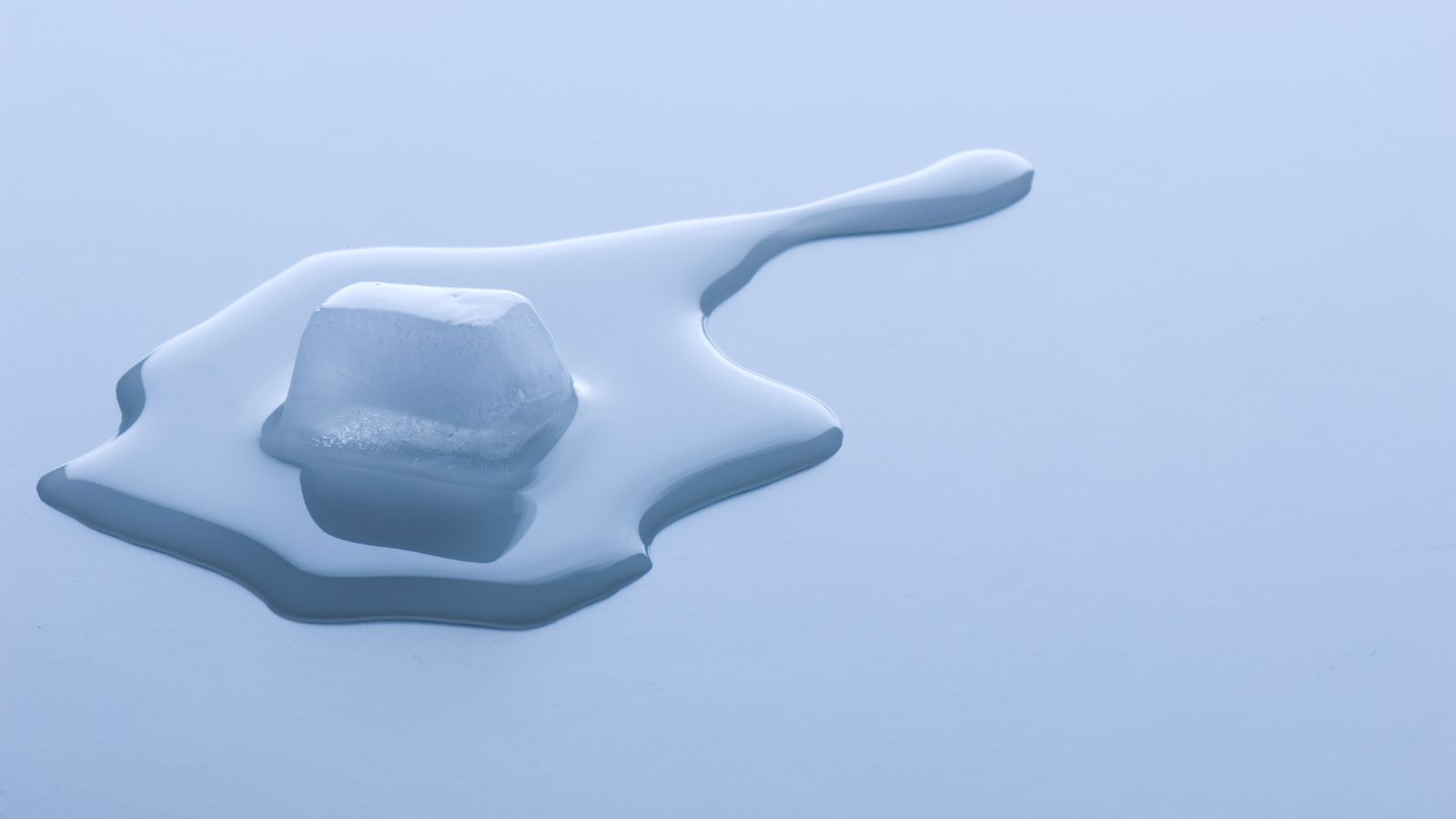 a melting ice cube on a white surface
